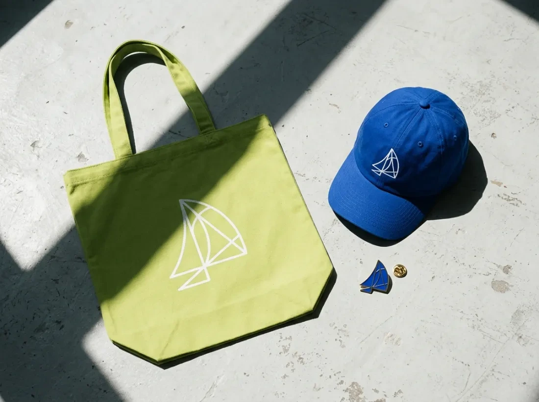 Concept tote, cap and pin carrying the abstract sail mark
